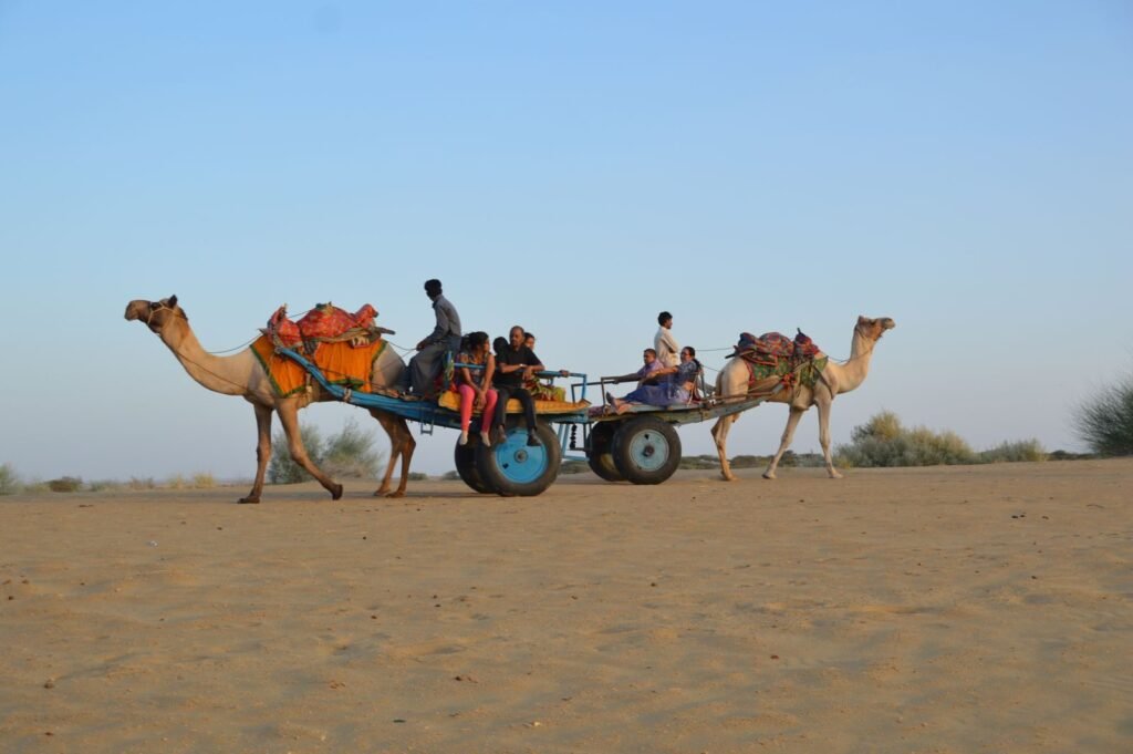 A group enjoys a camel cart ride through the picturesque sand dunes of Jaisalmer, India.